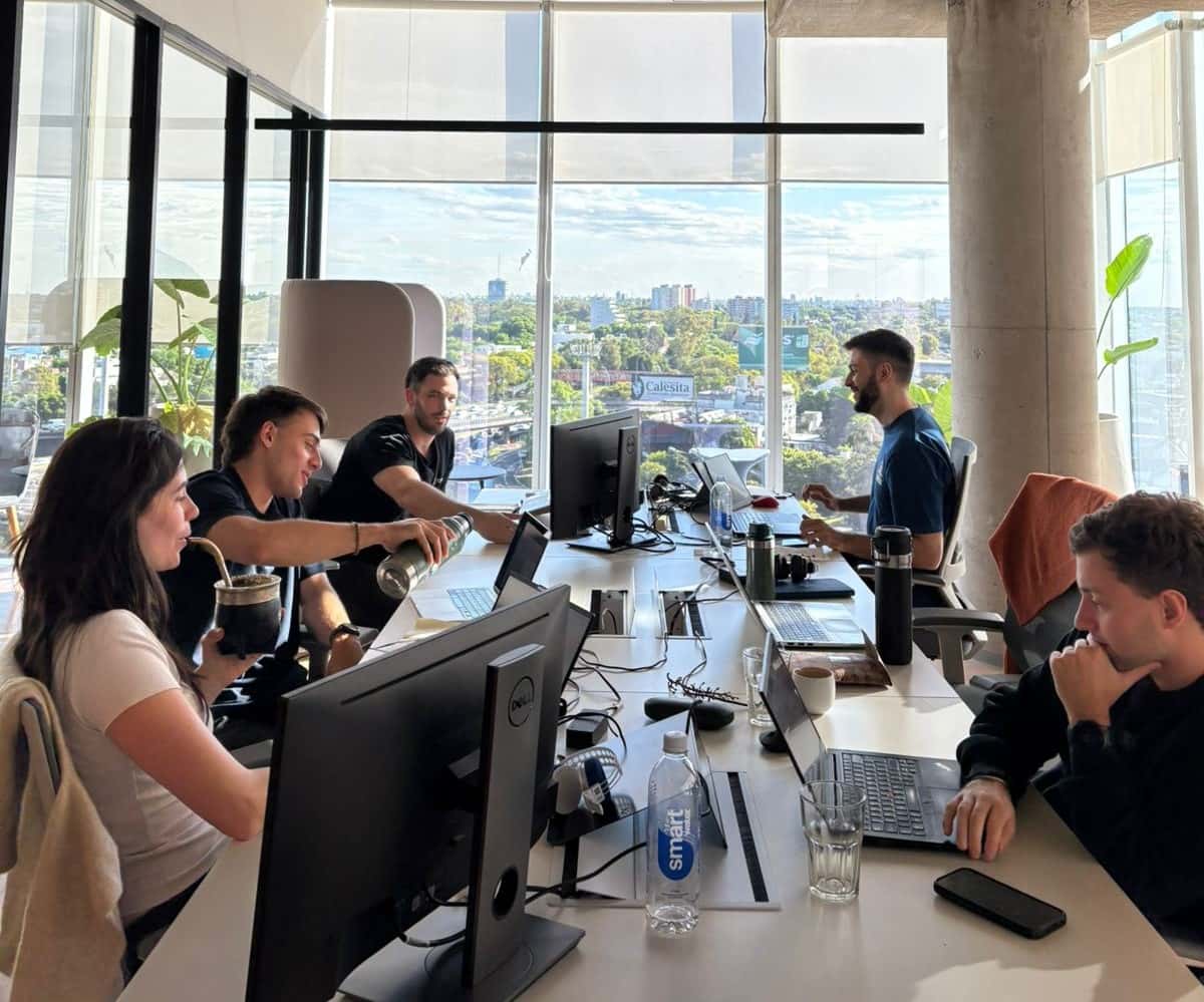 Group of Conexa employees working together around a table on laptops